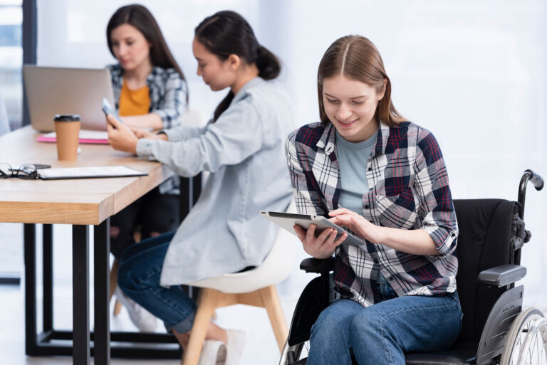 Teenager im Rollstuhl am Tablet mit Mitschüler*innen