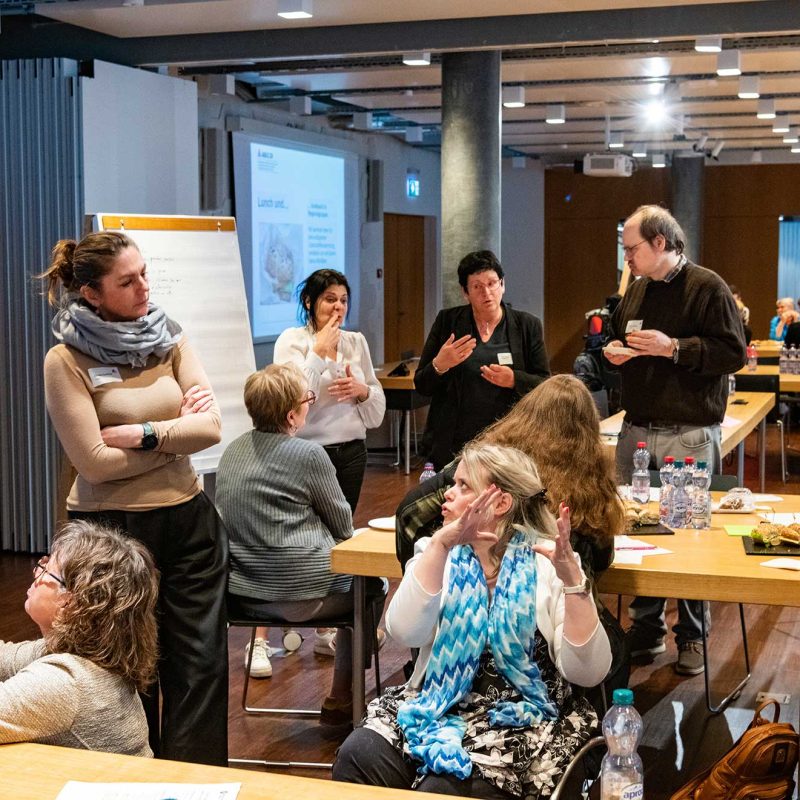 Workshop zur inklusiven Partizipation: Personen diskutieren in Gruppen, arbeiten an Flipcharts und bringen unterschiedliche Perspektiven in einen gemeinsamen Entscheidungsprozess ein. Foto © Agile