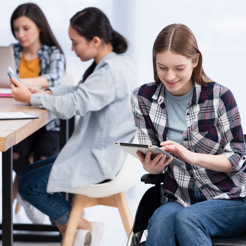 Teenager im Rollstuhl am Tablet mit Mitschüler*innen